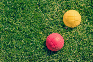 Bocce balls laying in grass.