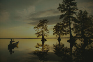 Man canoing through calm river.
