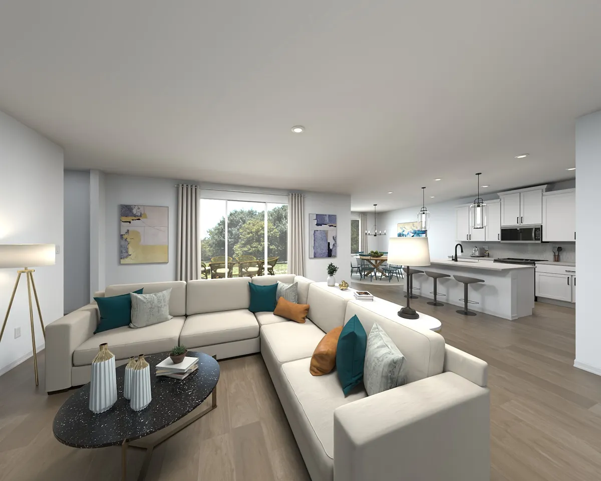 Modern open-concept living room and kitchen with light wood floors, white sectional sofas with colorful pillows, large windows with curtains, and contemporary decor. Kitchen features white cabinets and pendant lights.