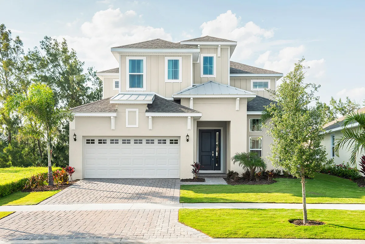 Modern two-story house with light-colored siding, a double garage, black front door, landscaped yard, palm trees, and a brick driveway under a clear blue sky.