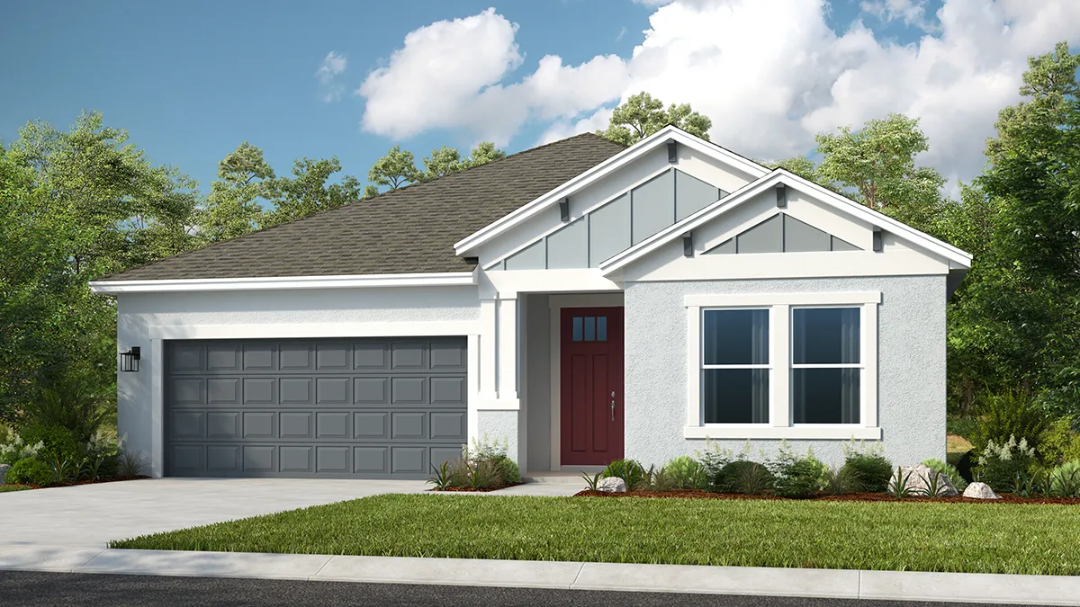 Modern single-story house with a gray gabled roof, white exterior, red front door, and a double gray garage. The yard is landscaped with grass, shrubs, and mulch, surrounded by trees under a partly cloudy sky.