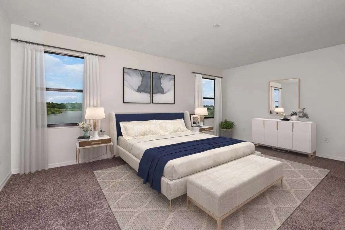 Modern bedroom with a large bed, navy blue accents, two windows with white curtains, a beige bench, bedside tables with lamps, a dresser with a mirror, and neutral-toned decor on plush carpet.
