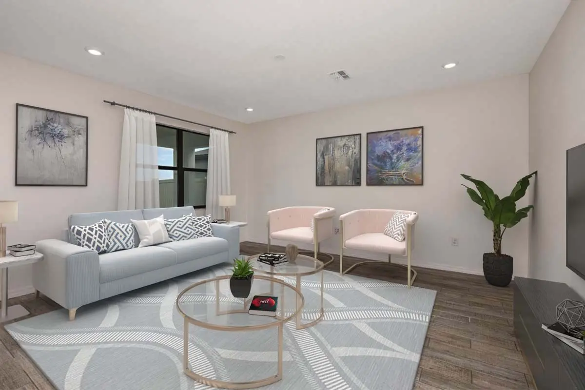 A modern living room with a light gray sofa, two pale pink chairs, a round glass coffee table, a potted plant, wall art, and a large window with white curtains. The floor is dark wood with a patterned rug.
