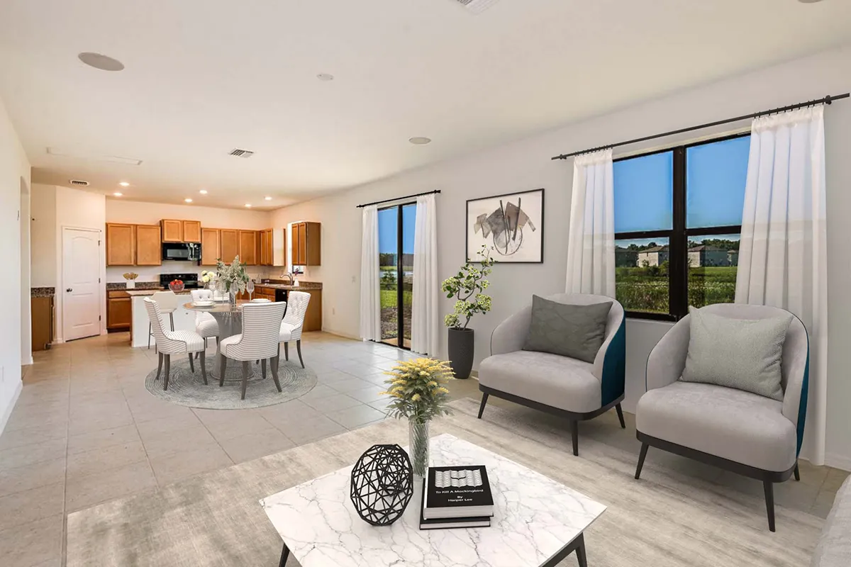 Modern open-concept living and dining room with light tile floors, neutral furnishings, a marble coffee table, large windows with white curtains, and a kitchen in the background.