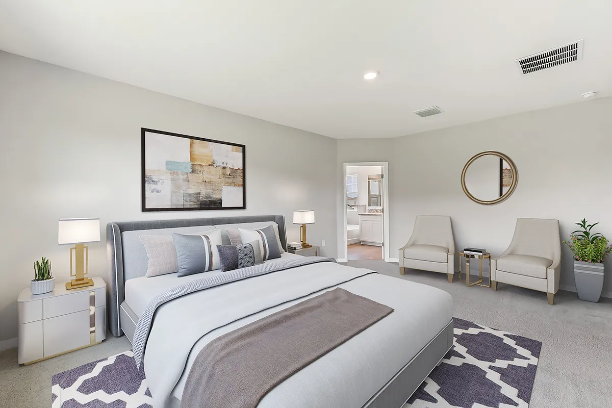 Modern bedroom with a gray bed, abstract wall art, two white chairs with a gold-framed mirror above, two nightstands with lamps and plants, and a doorway leading to a bathroom. Room has neutral tones and soft lighting.