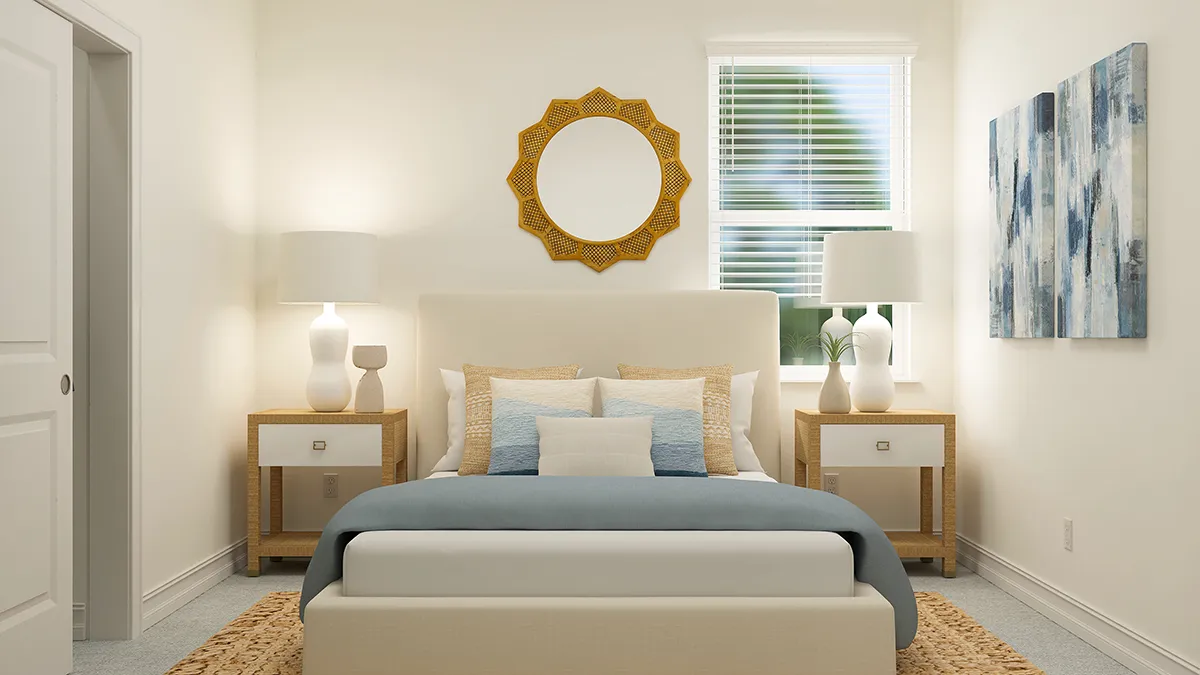 A modern bedroom with a beige bed, blue and cream bedding, two wooden nightstands with lamps, a round decorative mirror above the bed, abstract wall art, and a window with blinds letting in natural light.