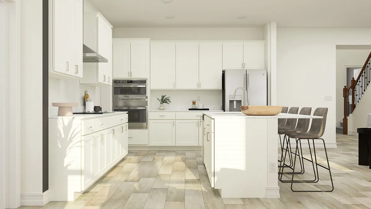 Modern kitchen with white cabinets, stainless steel appliances, a kitchen island with a wooden bowl, three gray barstools, and light wood flooring. Stairs and part of a living area are visible in the background.
