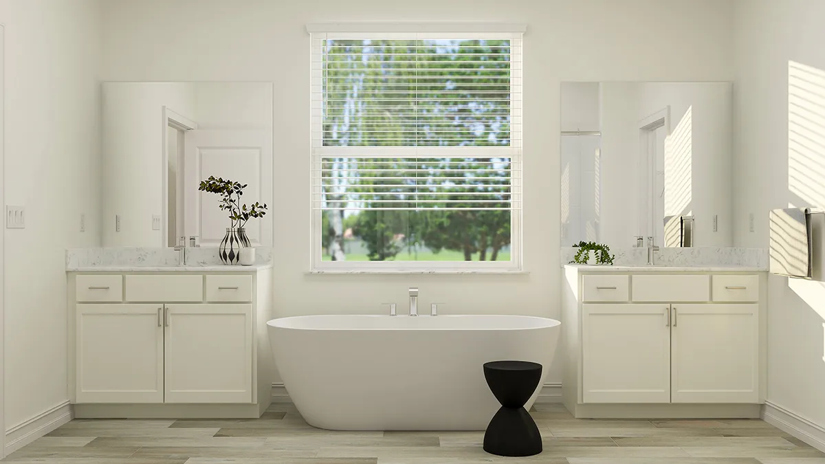 Modern bathroom with a freestanding white bathtub in the center, flanked by two white vanities with sinks and mirrors. A large window with blinds lets in natural light. A small black stool sits by the tub.