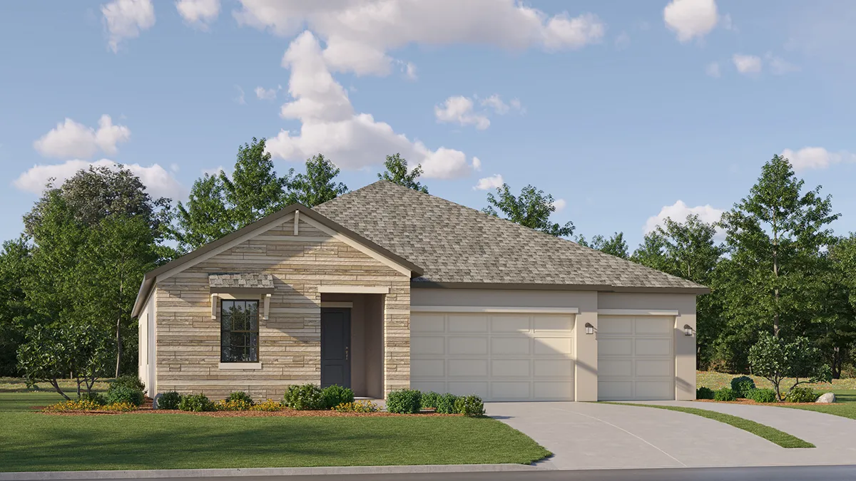 Single-story suburban house with light tan stone and siding exterior, gray shingle roof, three-car garage, and a neatly landscaped yard with grass and small shrubs, set against a backdrop of trees and blue sky with clouds.