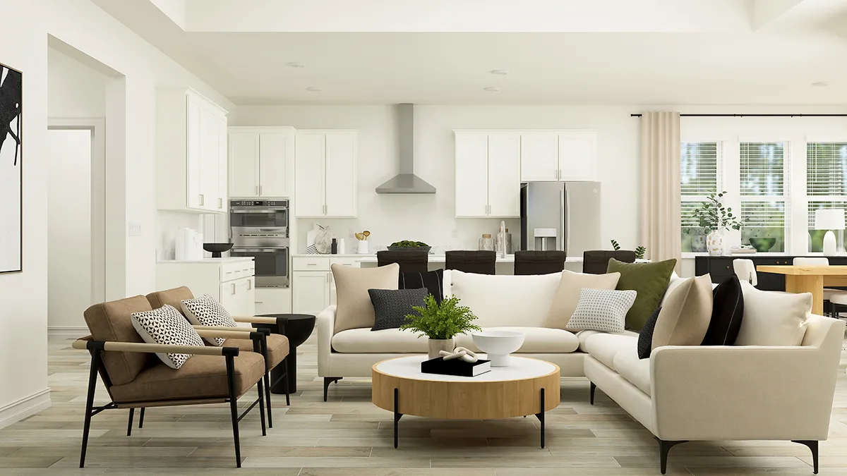 A modern open-concept living room and kitchen with neutral-toned sofas, a round wooden coffee table, black armchair, and minimalist decor. White cabinets and stainless steel appliances are visible in the kitchen area.