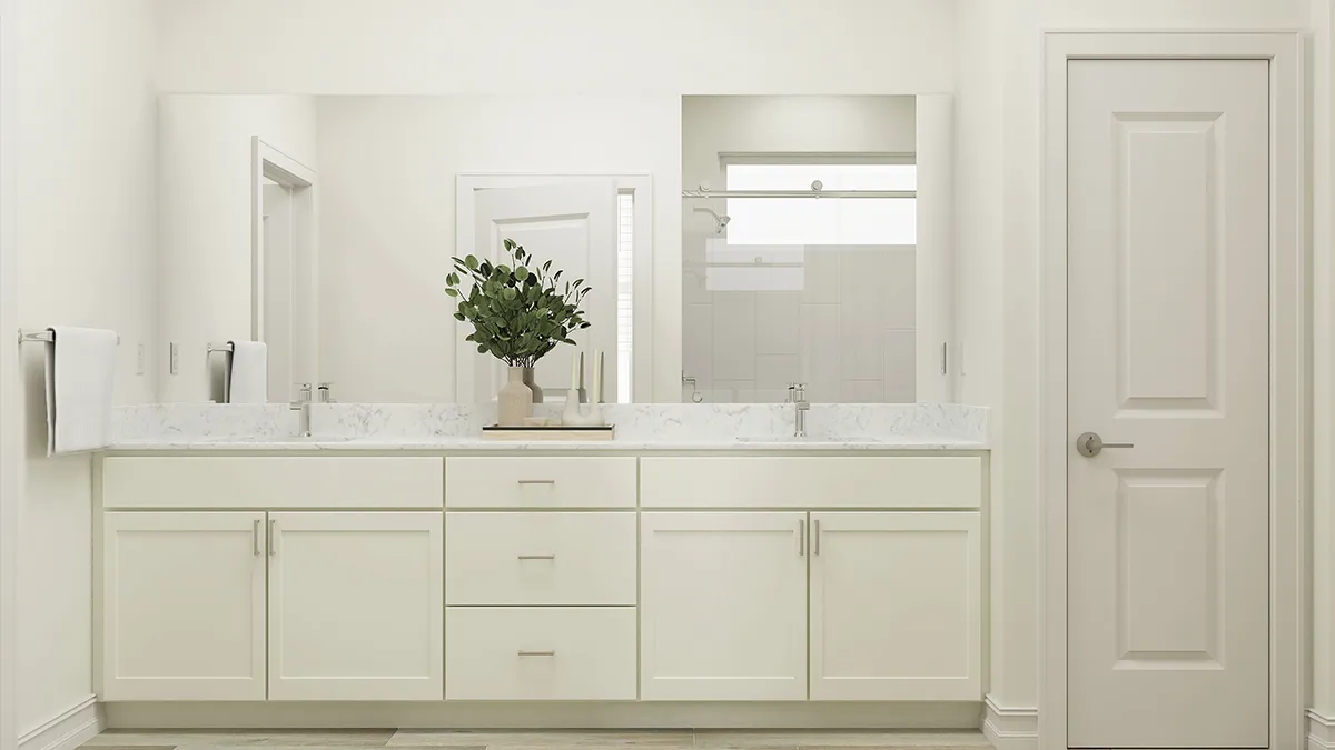 A modern bathroom features a long white vanity with two sinks, large mirrors above, and a central plant in a vase. There is a door on the right and neutral decor throughout.