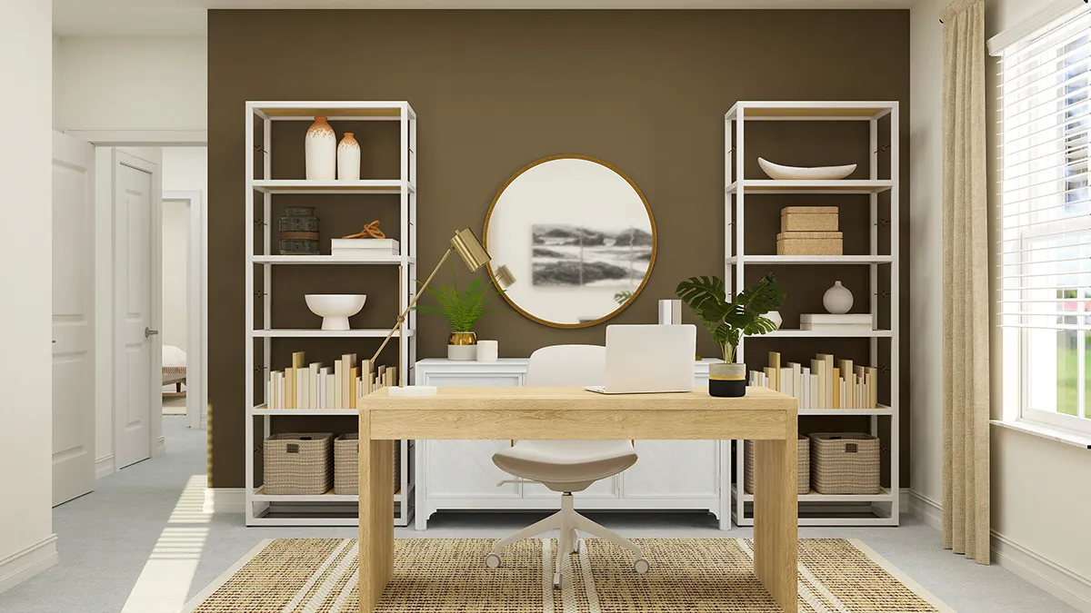 A modern home office with a wooden desk, laptop, lamp, and plant. Behind the desk are white bookshelves and a round mirror on a brown accent wall. Sunlight streams in through a window with beige curtains.