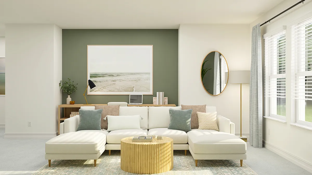 Modern living room with a white sectional sofa, assorted neutral and blue pillows, a round wooden coffee table, large beach artwork, oval mirror, floor lamp, and windows with sheer curtains letting in natural light.