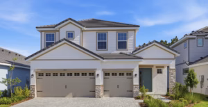 Modern two-story house with light-colored exterior, three-car garage, and neatly landscaped front yard under a blue sky.